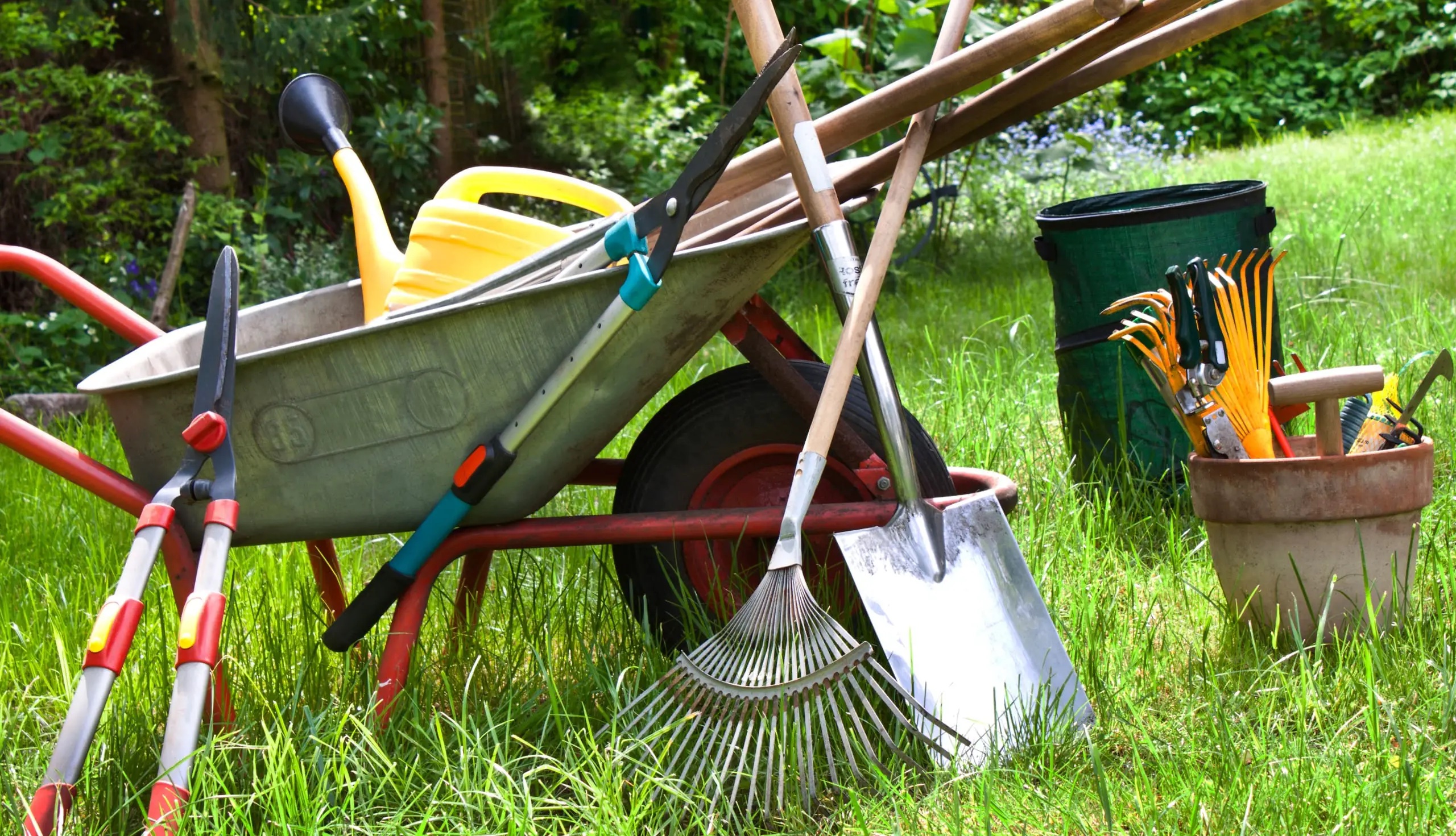 Picture of large garden hand tools around a wheelbarrow.