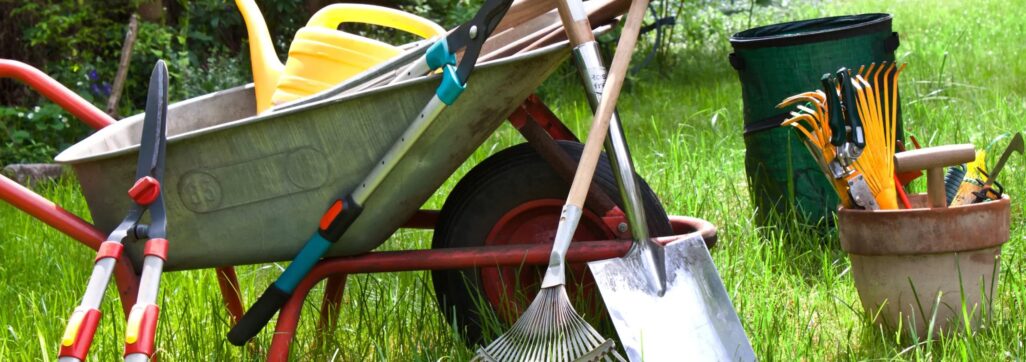 Picture of large garden hand tools around a wheelbarrow.